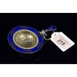 A silver tea strainer with blue and white enamelled decoration (small losses to enamel)