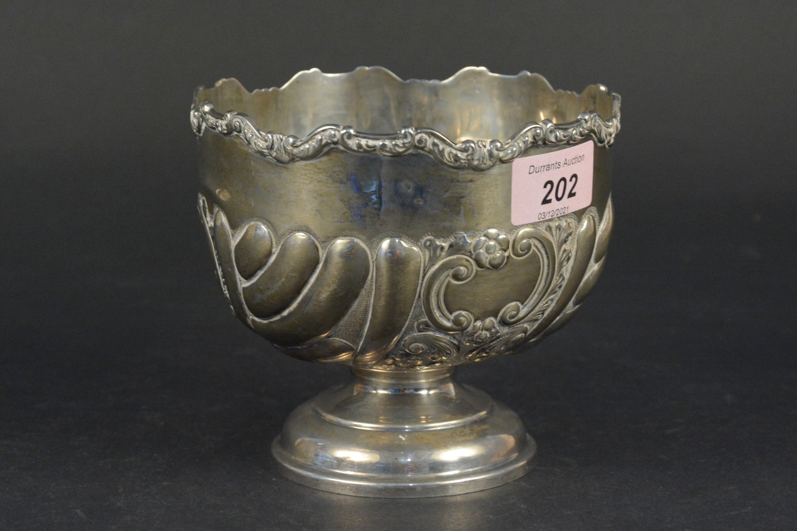 A silver bowl on pedestal base with applied and embossed floral decoration,