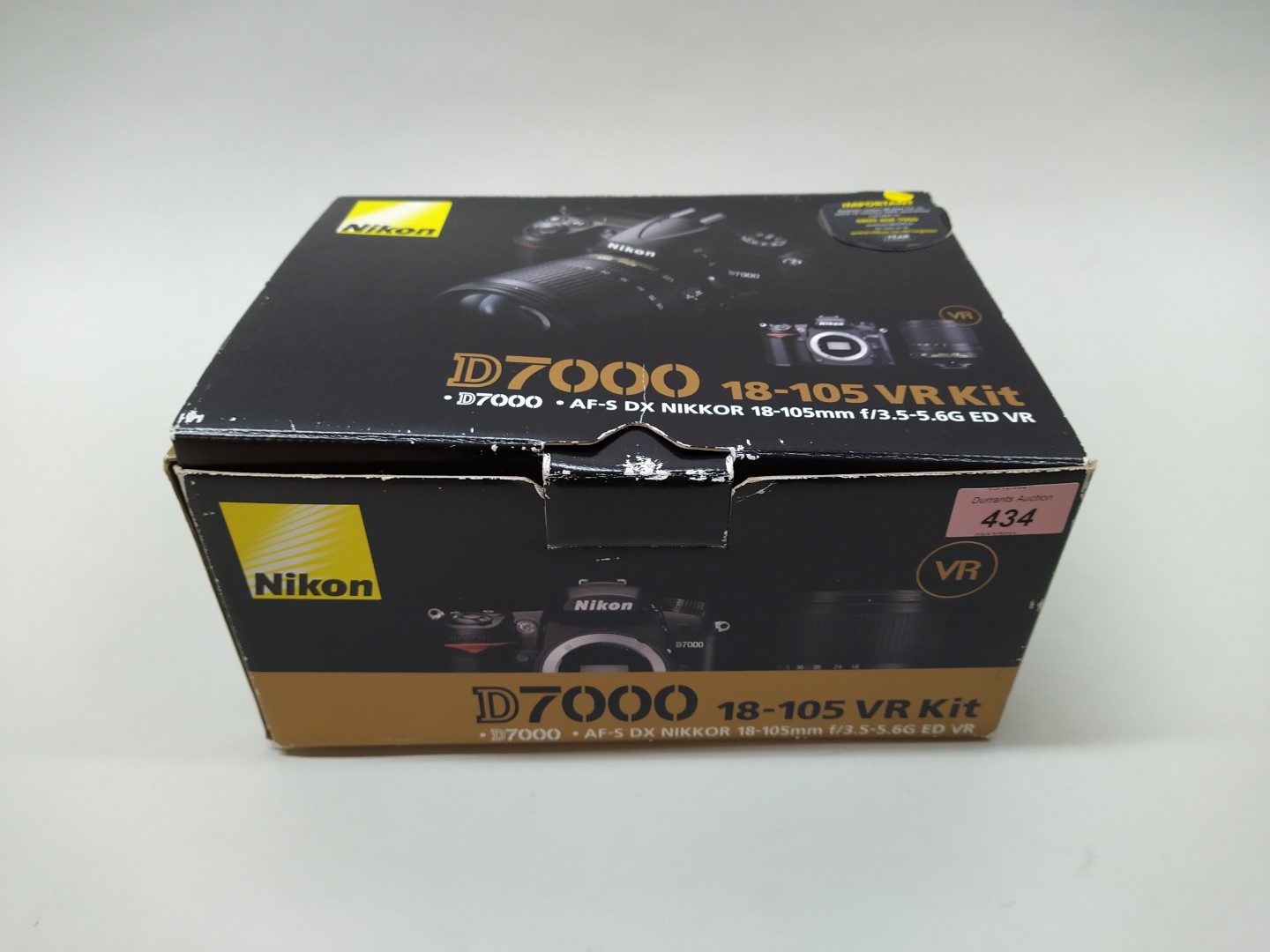 A Nikon D7000 camera body with a Nikon 18-77mm lens and charger in original box