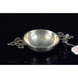 A silver tea strainer with pierced handles,
