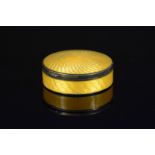 A silver circular trinket box with yellow guilloche enamel decoration to lid and main body,