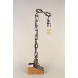 An unusual welded chain table lamp mounted on a wooden block,