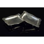 A pair of Omar Ramsden silver pin dishes with wavy edge and planished decoration on four bun feet,
