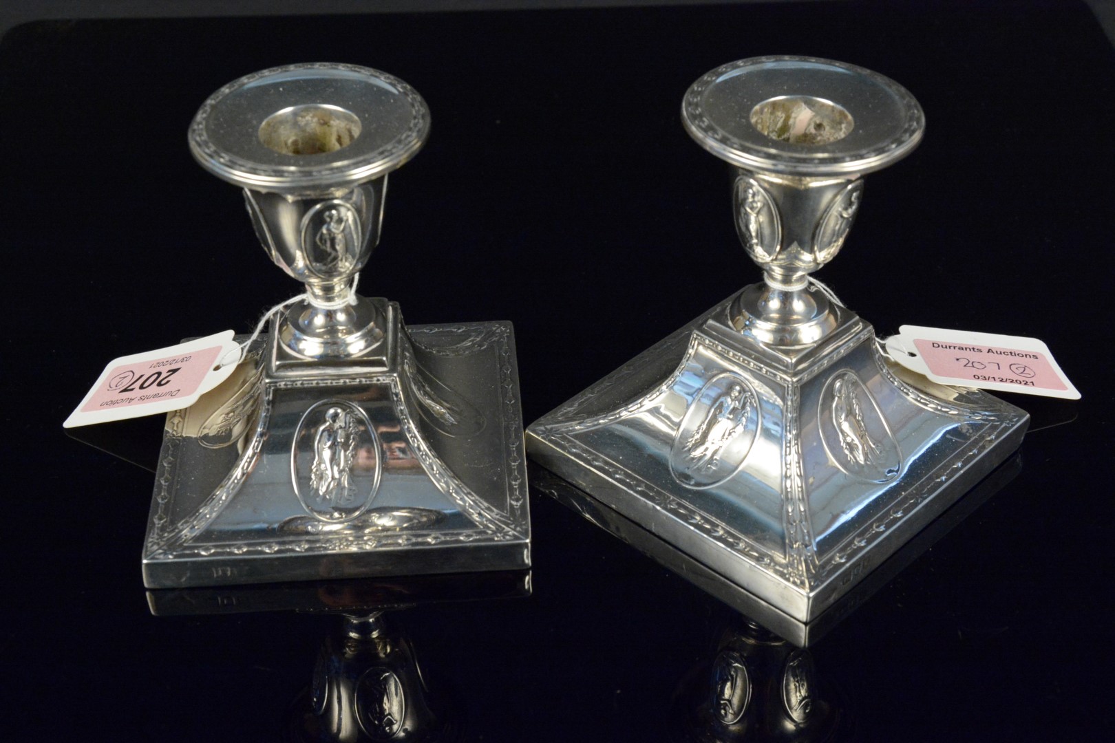 A pair of Adams style silver candlesticks with embossed images of Greek women and floral swag