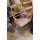 An Edwardian beech rocking chair with spindle back and cane work seat
