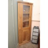 A modern pine corner cupboard with glazed top