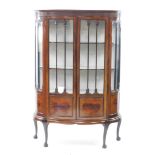 An early 20thC Chippendale style mahogany bowfront display cabinet, the pediment carved with blind