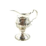 A George III silver cream jug, of ogee baluster form, embossed and engraved with homesteads,