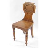 A Victorian oak hall chair, with a carved and scroll back and solid seat, raised on turned legs.