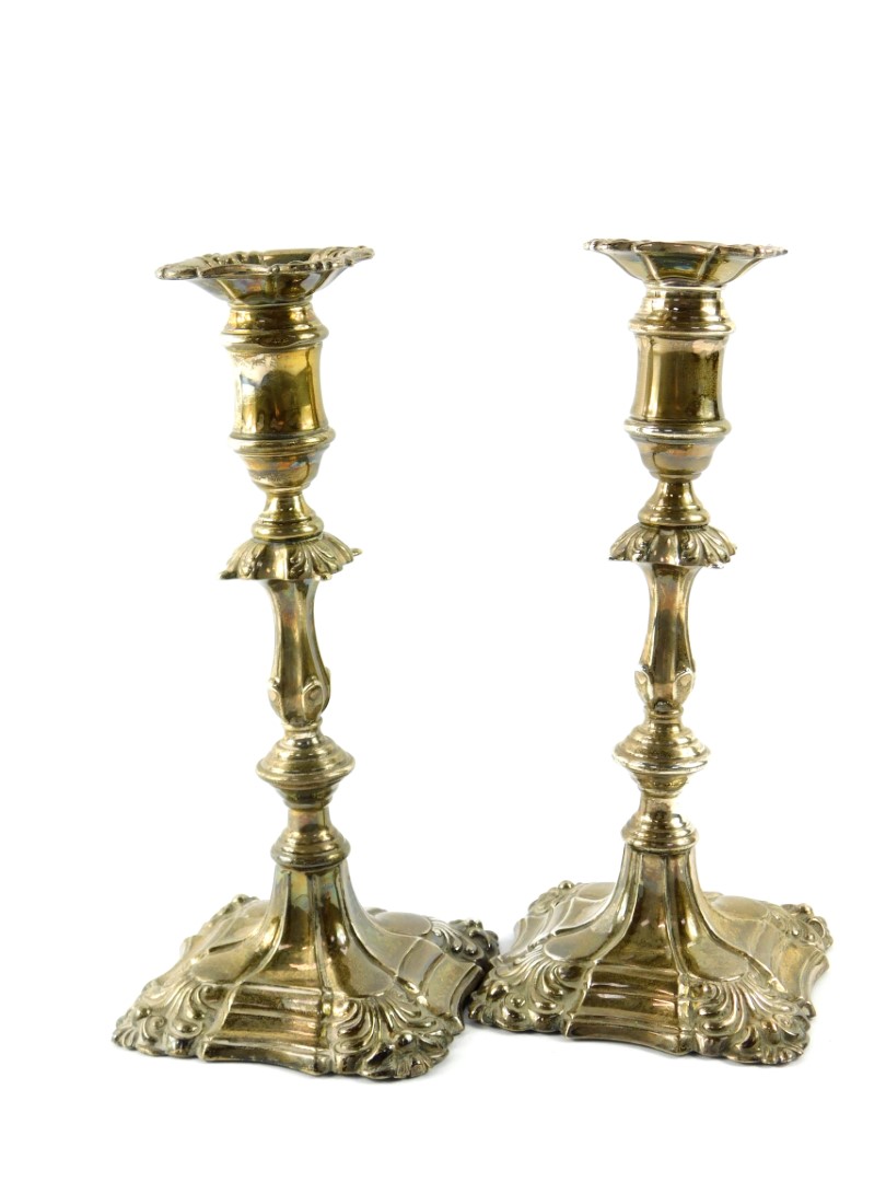 A pair of George III loaded silver candlesticks, of turned form with embossed scroll decoration,