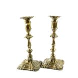 A pair of George III loaded silver candlesticks, of turned form with embossed scroll decoration,
