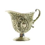 A Victorian silver cream jug, of footed helmet form, with a double scroll handle, embossed with