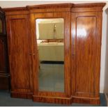 A Victorian flame mahogany break front compactum wardrobe, the outswept pediment over a glazed