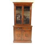 A Victorian mahogany cupboard bookcase, the outswept pediment over a pair of glazed doors opening to