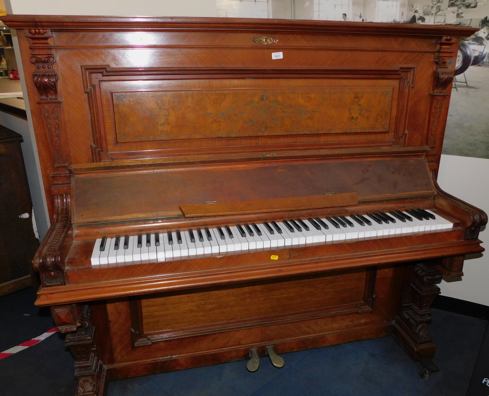 A Victorian walnut cased upright piano, makers label lacking, with carved pilasters, memorial plaque