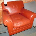 A red leatherette armchair, raised on bun feet.