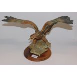 A Capodimonte sculpture of an eagle, with its wings outswept, raised on a wooden base.