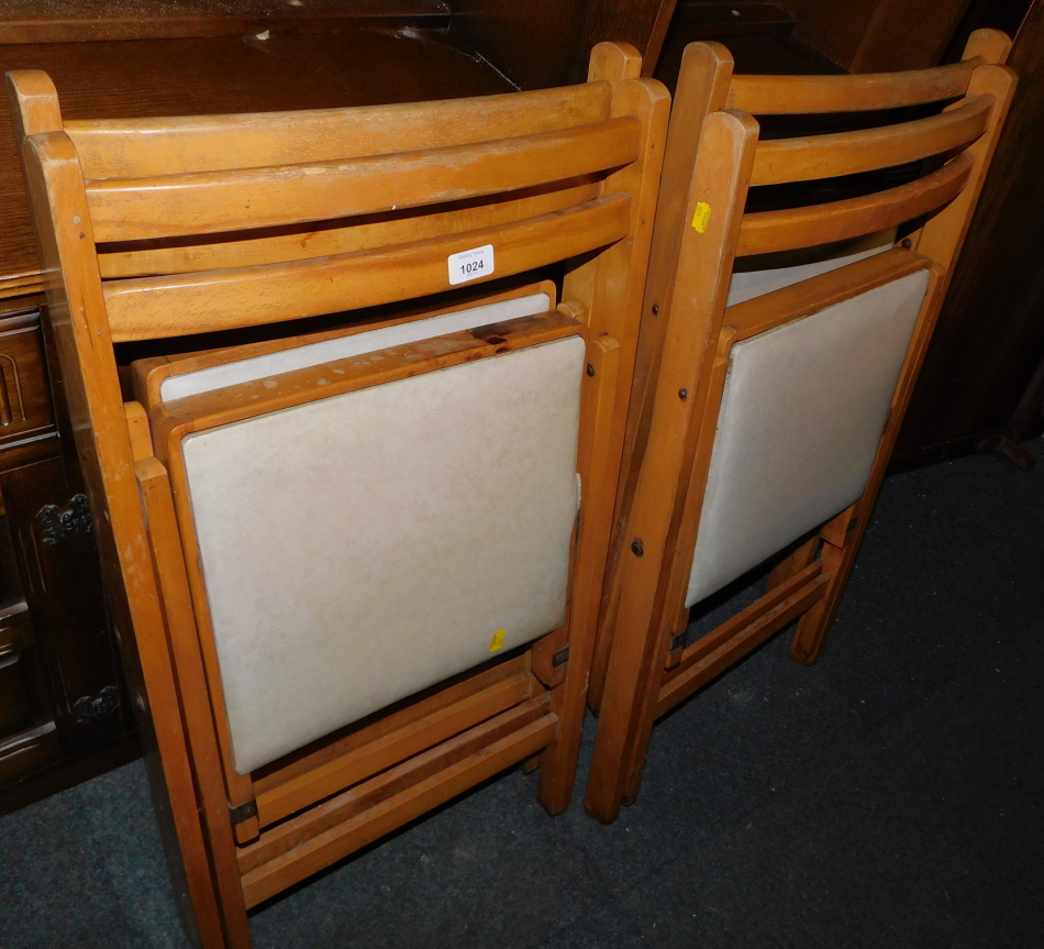 A set of four mid 20thC beech framed folding chairs, with cream vinyl seats.