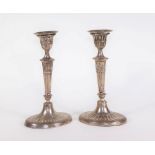 A pair of Edwardian silver Adam style candlesticks, with oval reeded sconces and urn shaped holders,