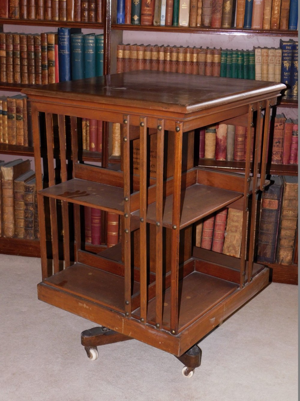 A Edwardian mahogany revolving bookcase, with slatted supports on X shaped base with ceramic