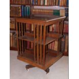 A Edwardian mahogany revolving bookcase, with slatted supports on X shaped base with ceramic