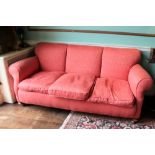 An Edwardian three seater sofa, re-upholstered in pink damask fabric, on bun feet with castors,