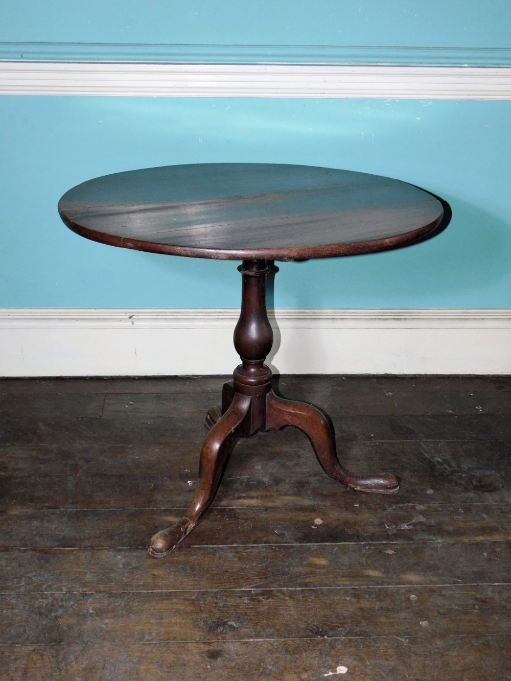 An early 19thC oak occasional table, the circular planked tilt top on a turned column and a tripod