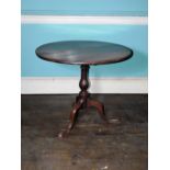 An early 19thC oak occasional table, the circular planked tilt top on a turned column and a tripod