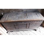 A large 17thC carved poker work walnut coffer, the lid with iron strap hinges and carved figural and