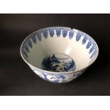 An 18thC Chinese punch bowl, handpainted with blue on white having a central reservoir of trees,