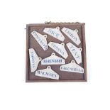 A wooden board containing nine pottery bin labels, inscribed Malmsey Calcavella, Vinonia, Rhenish,