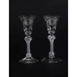 A pair of mid 18thC Jacobite wine glasses, with engraved thistle bowls, each having a white rose and