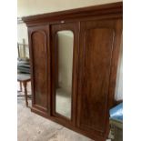 A Victorian mahogany triple wardrobe, with moulded cornice, mirrored centre door, fitted interior, a
