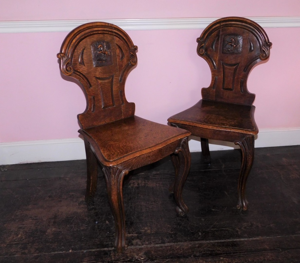 A pair Victorian oak hall chairs, the shield shaped back with carved Pegasus crest, the solid