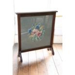 An Edwardian mahogany firescreen, inset with a later tapestry, floral panel on tapering end