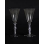 A pair of early 19thC wine glasses with trumpet shaped bowls, each engraved with a band of