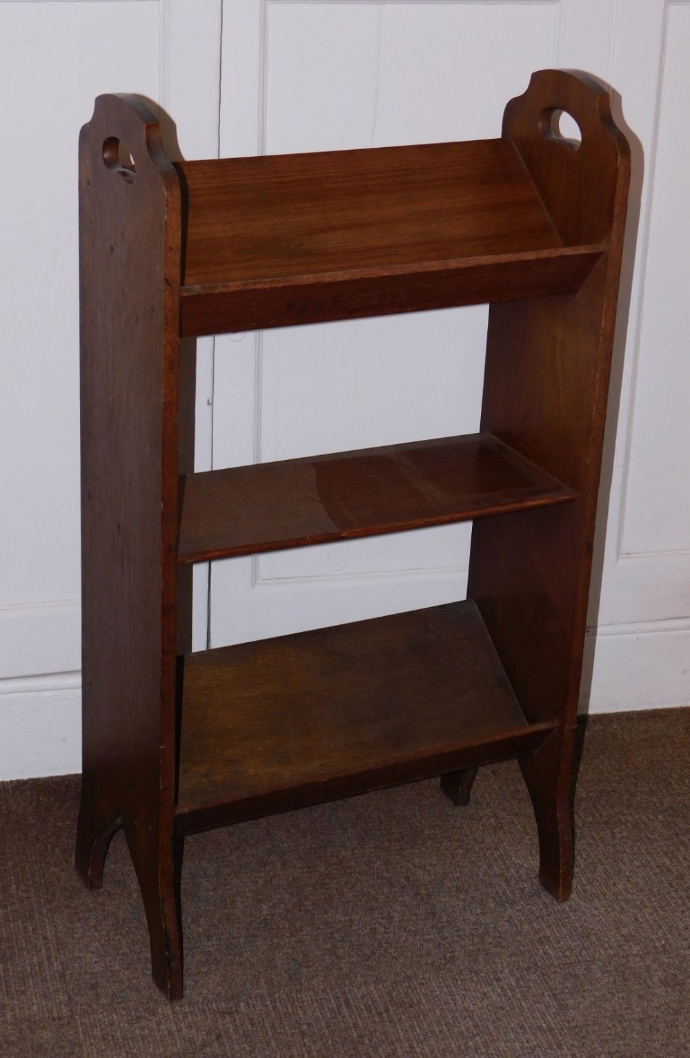 An early 20thC oak book stand, with pierced side handles and shaped end supports 91cm high, 50cm