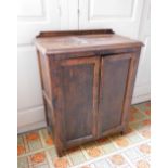 A stained pine and ply side cabinet, with a raised top, two panelled doors enclosing shelves, on end