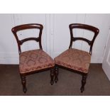 A pair of Victorian mahogany balloon back dining chairs, each with a padded seat on turned