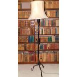 A 20thC wrought iron standard lamp, decorated with scrolls on tripod base, with a cream shade, 192cm