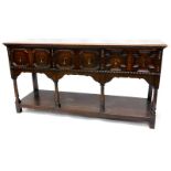 An early 20thC oak dresser base, the top with a moulded edge above three panelled drawers, on turned