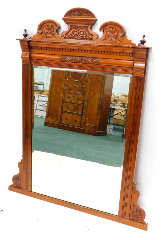 A late 19th/ early 20thC walnut overmantel mirror, with a shaped crest and a rectangular bevelled