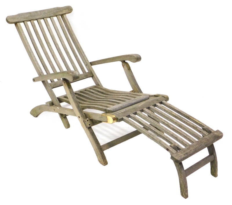 A modern teak steamer type chair, with a hinged foot rest and slatted back.