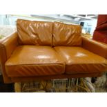 A tan coloured vintage style leather two seater sofa, on square tapering legs, 132cm wide.