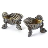 A pair of silver plated shell shaped salts, each on stylised dolphin supports, 7cm wide.