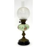 A brass oil lamp, with a clear and frosted globular shade, the green opaque glass reservoir