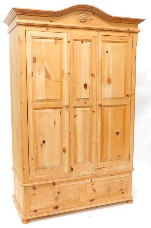 A waxed pine double wardrobe, with shaped cornice and two panelled doors, the base with two