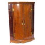 An early 19thC oak and mahogany bow fronted corner cabinet, the doors with H shaped hinges enclosing
