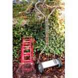 A pair of red painted car ramps, fire grate and a cylinder mower.