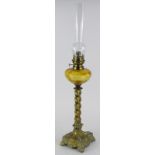 A continental brass oil lamp, with an amber tinted reservoir, spirally twisted column and square